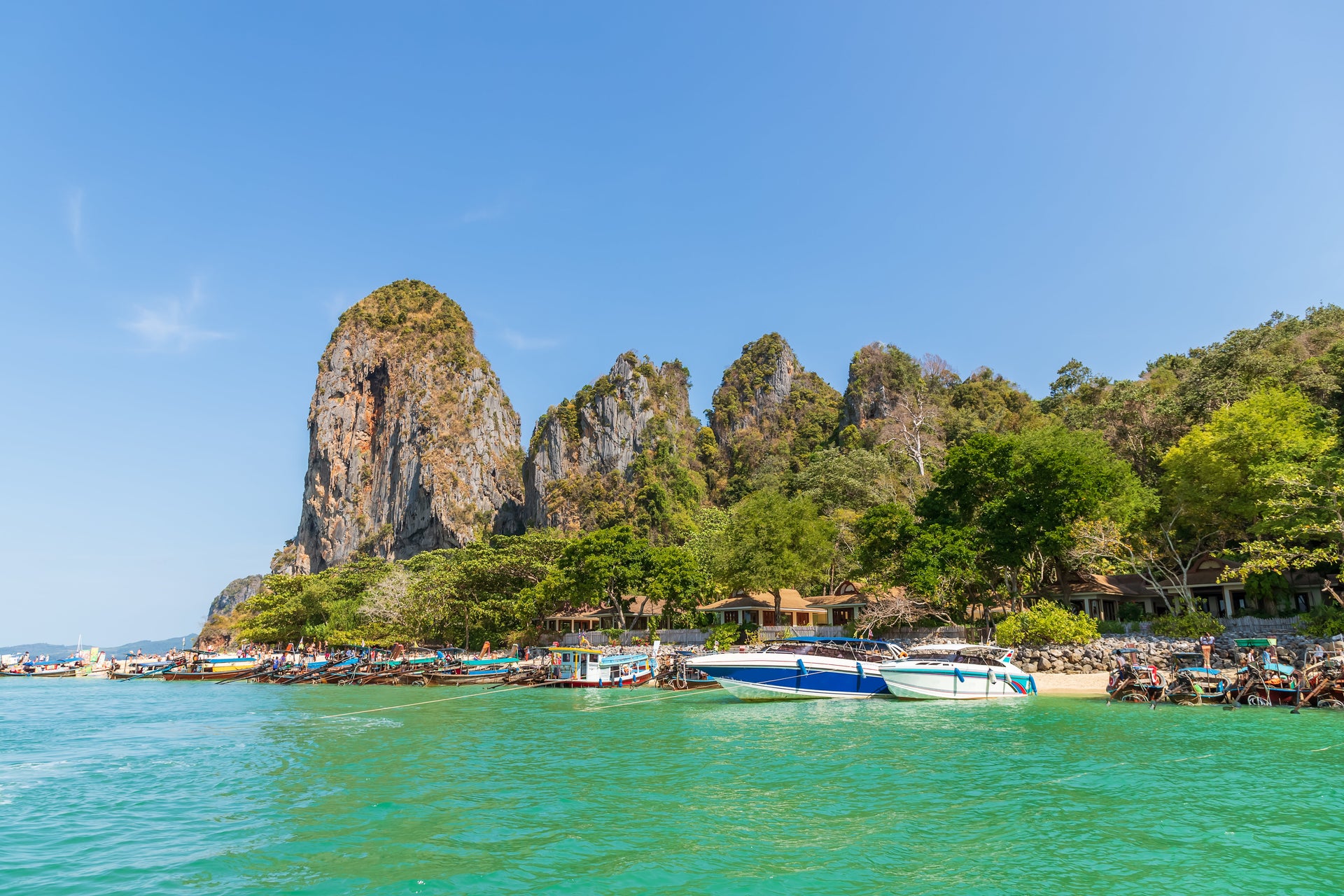 Strand in Phuket. Bunte Boote und große Felsen mit Blauem Wasser.